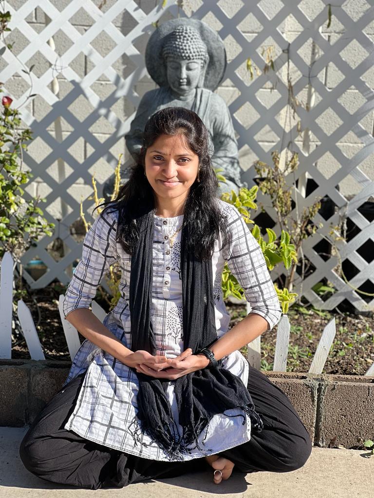Jayanthi Bommana standing outdoors beside a garden trellis